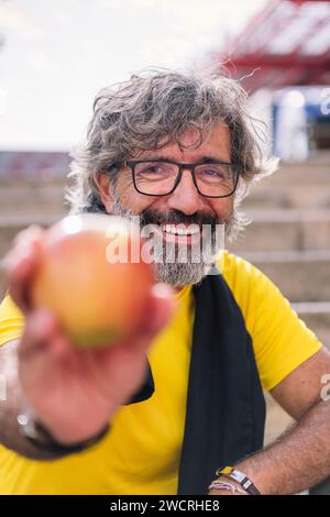 Ein Senior-Sportmann zeigt nach dem Training einen Apfel Stockfoto
