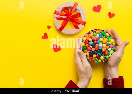 Weibliche Hände mit köstlichen Süßigkeiten in der Schachtel auf farbigem Hintergrund. Stockfoto