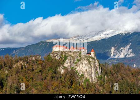 Ein majestätisches Schloss steht stolz auf einem üppigen, baumbewachsenen Hügel inmitten einer atemberaubenden Berglandschaft in Bled, Slowenien, Stockfoto