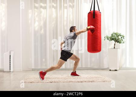 Starker Mann, der zu Hause einen Boxsack schlägt Stockfoto