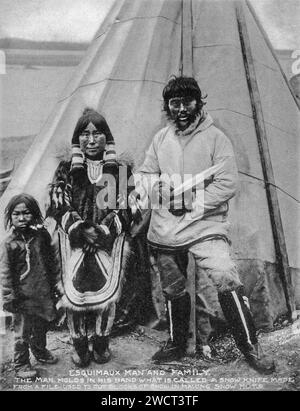 Ein Foto einer Inuit-Familie aus dem Jahr 1901, aufgenommen von C W Mathers auf einer Expedition in den hohen Norden Kanadas und veröffentlicht in seinem Buch „The Far North“. Mathers untertitelte dieses Foto: Eskimaux [Inuk] Mann und Familie. Der Mann hält in der Hand ein so genanntes Schneemesser, das aus einer Feile hergestellt wird, um Schneeblöcke zu schneiden, um Schneehütten [Iglus] zu bauen. Stockfoto