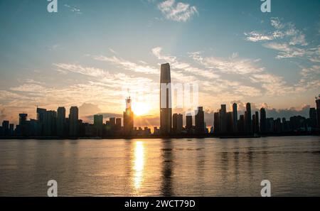 Der Sonnenaufgang am Wuchang-Strand des Yangtze-Flusses mit Wolkenkratzern am Ufer des Flusses. Stockfoto