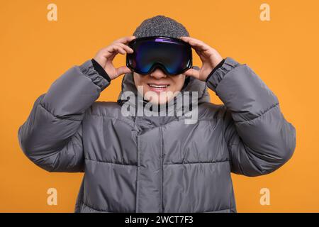 Wintersport. Glücklicher Mann in Skibrille auf orangem Hintergrund Stockfoto