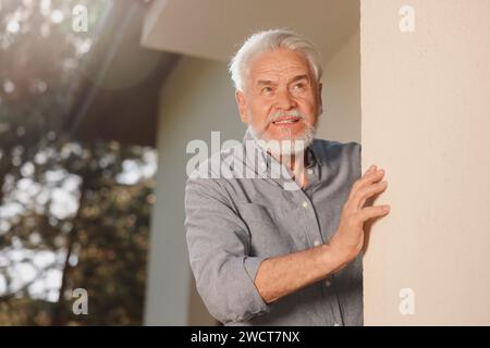 Porträt eines älteren Mannes in der Nähe des Hauses draußen, Platz für Text. Nerviger Nachbar Stockfoto