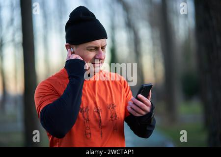 Läufer, der während des Laufens einen Anruf über Kopfhörer entgegennimmt oder Musik auflegt Stockfoto