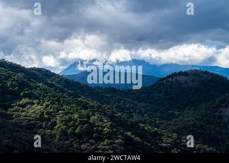 Ein atemberaubender Blick auf eine üppige Bergkette, die von dramatischen Wolken umgeben ist und die Pracht der Natur unterstreicht Stockfoto