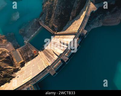 Blick von oben auf einen massiven Staudamm mit einem Stausee in den Bergen bei klarem Wetter Stockfoto