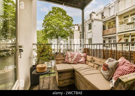 Kleine Couch und Couchtisch auf gemütlichem Balkon in einem modernen Apartment mit geschlossener Tür und Geländer Stockfoto