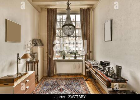 Elegantes Zimmer im Vintage-Stil mit einem Kronleuchter, gerahmten Kunstwerken und einer Auswahl an silbernen Teekannen auf einem hölzernen Sideboard. Stockfoto