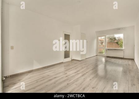 Ein unbelegter Raum mit modernem Holzboden, weißen Wänden und einem großen Fenster für Tageslicht, ideal für Immobilieneinträge. Stockfoto