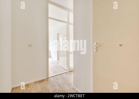 Helles und minimalistisches Innenleben mit einer weißen Glastür, die teilweise offen ist und einen Blick in einen angrenzenden Raum mit Holzfußboden freigibt. Stockfoto