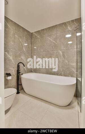 Ein elegantes Badezimmer mit einer eleganten freistehenden Badewanne mit stilvollen Marmorfliesen und minimalistischem Design. Stockfoto