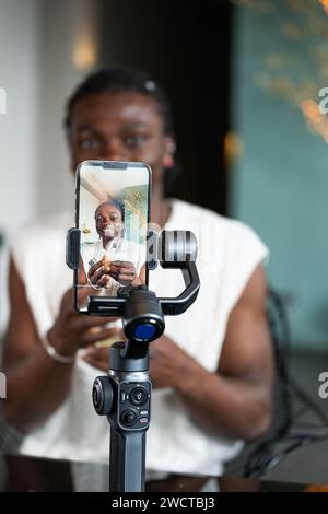 Engagierter Schwarzer erstellt ein Tutorial-Video zur Hautpflege mit einem Handykarmbal mit verschwommenem Hintergrund Stockfoto