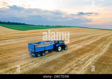Ein Traktor mit Anhänger fährt aus der Luft über ein landwirtschaftlich genutztes Feld Stockfoto