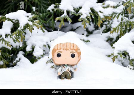 Funko Pop Actionfigur von Hobbit Sam mit Schwert und Phialenlicht aus dem Fantasy-Film der Herr der Ringe. Winterwald, Schneewehungen, grüne Wälder. Stockfoto