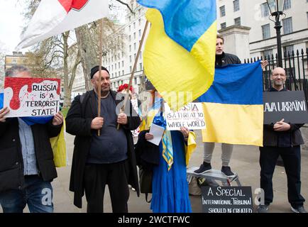 Gegenprotestierende halten ukrainische Flaggen, während sich Demonstranten gegen Großbritanniens Beteiligung am Krieg in der Ukraine in der Nähe der Londoner Downing Street versammeln. Stockfoto