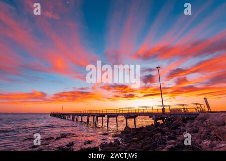 Badesteg mit Fischern während des Sonnenaufgangs, während Sie von der Küste aus gesehen werden, Limestone Coast, South Australia Stockfoto