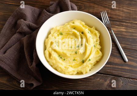 Kartoffelpüree, gekochtes Püree mit Butter und Gemüse in einer weißen Schüssel auf Holztisch. Comfort Food für gesunde Ernährung. Rustikaler Stil, Nahsicht Stockfoto