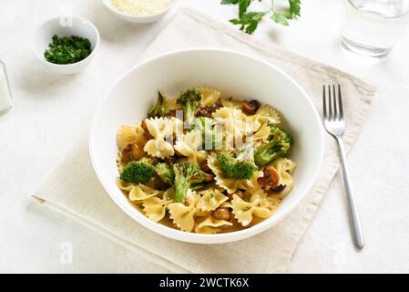 Farfalle Pasta mit gebratenem Brokkoli und Pilzen in einer Schüssel auf weißem Hintergrund. Hausgemachtes, zubereitetes Gericht von Farfalle-Pasta mit geröstetem Brokkoli und s Stockfoto