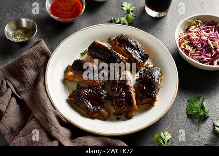 Pork ribs on plate over dark stone background. Close up view Stock Photo