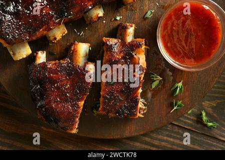 Nahaufnahme von Barbecue Schweinerippchen auf dem Schneidebrett über hölzernem Hintergrund. Draufsicht, flach Stockfoto