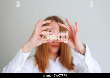 Glückliches Mädchen, das die Buchstaben JA in den Händen hält. Konzentrieren Sie sich auf Ja Stockfoto