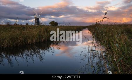 Farbenfroher, bewölkter Himmel über Hammelmühle und Schilfbeeten in Halvergate Marshes in der Norfolk Broads i Mutton's Mill, November 2023 Stockfoto