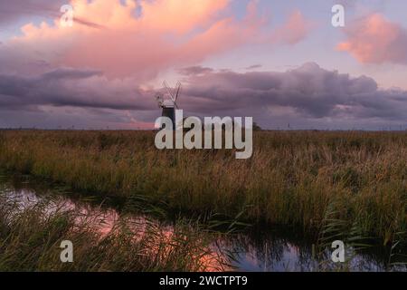 Farbenfroher, bewölkter Himmel über Hammelmühle und Schilfbeeten in Halvergate Marshes in der Norfolk Broads II Mutton's Mill, November 2023 Stockfoto