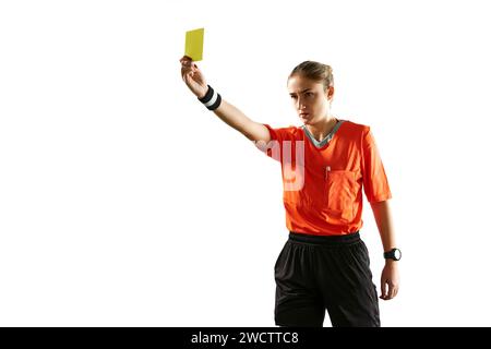 Ernsthafte und konzentrierte junge Frau, Fußballschiedsrichter, die das Spiel kontrolliert, zeigt gelbe Karte als abnehmendes Symbol vor weißem Studiohintergrund Stockfoto