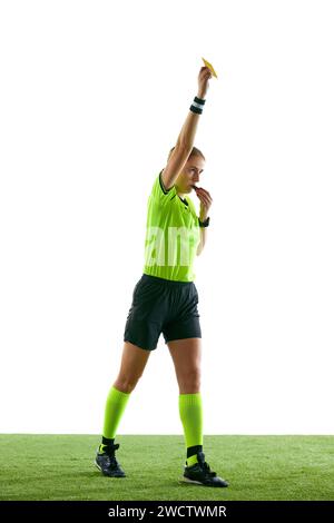 Ernsthafte Frau, Fußball-Schiedsrichter, Hand heben, Spiel stoppen und gelbe Karte als Warnung vor weißem Studiohintergrund zeigen Stockfoto