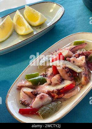 Ein verführerischer mediterraner Kraken-Salat mit bunten Paprika und frischen Zitronenscheiben. Stockfoto