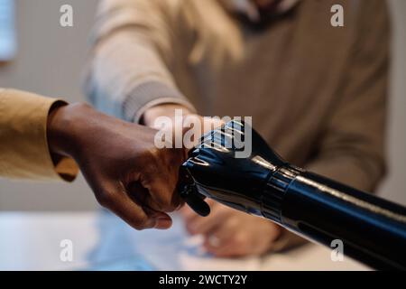 Zwei Menschen mit birassischer Prothese und eine Person mit einer Faust, die sich gegenseitig prallt Stockfoto