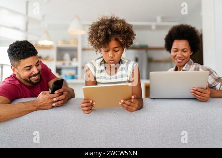 Familie mit Laptop, Tablet und Smartphone zu Hause, jeder nutzt digitale Geräte Stockfoto