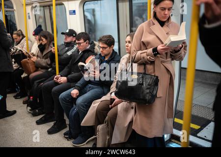 Die Londoner Pendler lesen Bücher, während sie in der Londoner U-Bahn während der Hauptverkehrszeit in einer belebten Kutsche reisen, England, Großbritannien Stockfoto