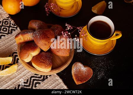 Teezeit mit gelben Tassen und hausgemachten herzförmigen Muffins. Cupcakes mit Orangengeschmack zum Valentinsfrühstück Stockfoto