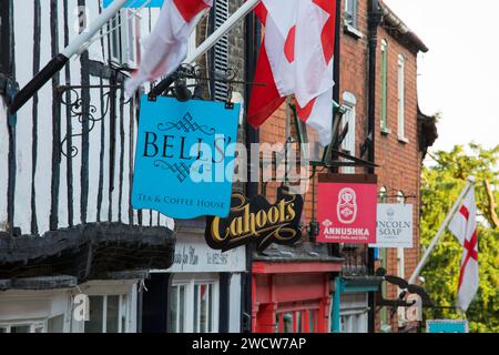 Lincoln, Lincolnshire, England. Die Fachwerkfassade der Bells, ein traditionelles Teestube und Kaffeehaus auf dem steilen Hügel, Ladenschilder dahinter. Stockfoto