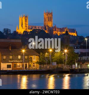 Lincoln, Lincolnshire, England. Blick über das ruhige Wasser des Flusses Witham am Brayford Pool zur beleuchteten Lincoln Cathedral in der Abenddämmerung. Stockfoto