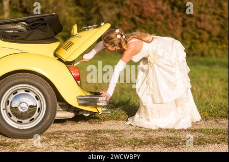 Lustige, ungewöhnliche, stilvolle, originelle Fotos mit Rollenumkehr eines jungen, attraktiven Brautpaares mit wunderschönen Veteranenautos in der Natur. Stockfoto