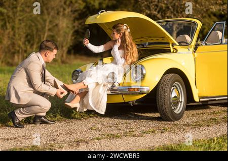 Lustige, ungewöhnliche, stilvolle, originelle Fotos mit Rollenumkehr eines jungen, attraktiven Brautpaares mit wunderschönen Veteranenautos in der Natur. Stockfoto