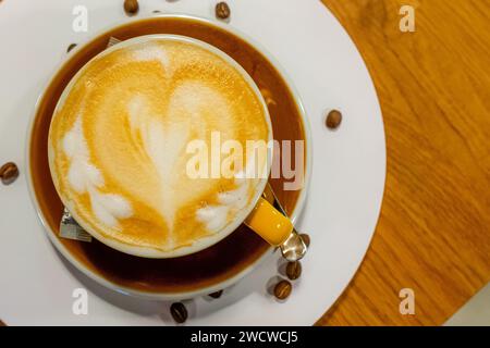 Eine dampfende Tasse frisch gebrühten Kaffees wird elegant in einer makellos weißen Keramikschale präsentiert, die auf einer passenden Untertasse liegt Stockfoto