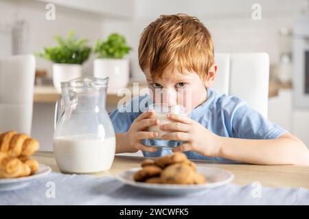 Der süße Junge trinkt frische Milch zum Frühstück. Stockfoto