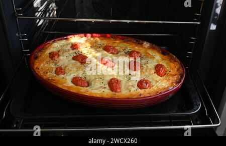 Home Kochen Sie einen Cottage Pie aus Rindfleisch und garniert mit Kartoffelpüree mit Lauch, Käse und kleinen Tomaten Stockfoto