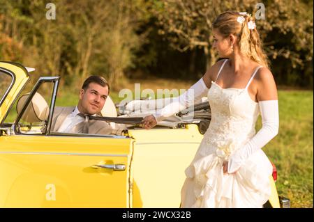 Lustige, ungewöhnliche, stilvolle, originelle Fotos mit Rollenumkehr eines jungen, attraktiven Brautpaares mit wunderschönen Veteranenautos in der Natur. Stockfoto