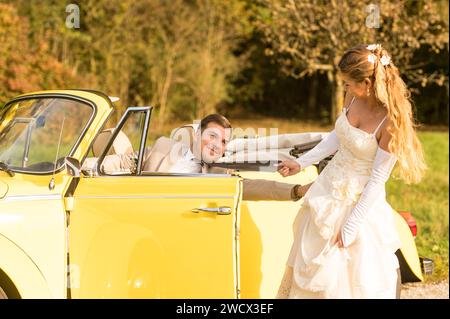 Lustige, ungewöhnliche, stilvolle, originelle Fotos mit Rollenumkehr eines jungen, attraktiven Brautpaares mit wunderschönen Veteranenautos in der Natur. Stockfoto