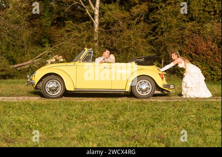 Lustige, ungewöhnliche, stilvolle, originelle Fotos mit Rollenumkehr eines jungen, attraktiven Brautpaares mit wunderschönen Veteranenautos in der Natur. Stockfoto