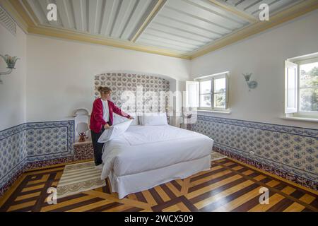 Portugal, Alentejo, Melides, Putzfrau, die das Bett in einer Suite des Vermelho Hotels herstellt, Boutique-Hotel des Schuhdesigners Christian Louboutin, dekoriert mit Azulejos und eingelegten Holzböden Stockfoto