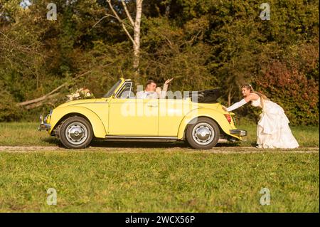 Lustige, ungewöhnliche, stilvolle, originelle Fotos mit Rollenumkehr eines jungen, attraktiven Brautpaares mit wunderschönen Veteranenautos in der Natur. Stockfoto