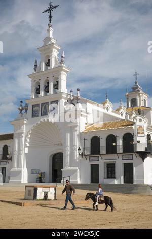 Spanien, Andalusien, El Rocío, Mann, der seine kleine Tochter auf einem Pony in einer Sandstraße, wo die Einsiedelei Nuestra señora del Rocío steht, führt Stockfoto