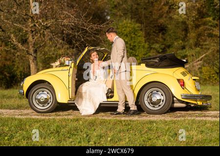 Lustige, ungewöhnliche, stilvolle, originelle Fotos mit Rollenumkehr eines jungen, attraktiven Brautpaares mit wunderschönen Veteranenautos in der Natur. Stockfoto