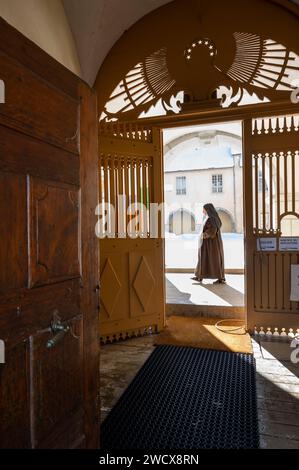 Frankreich, Haute Savoie, Aravis-Massiv, Le Reposoir, die Chartreuse du Reposoir heißt heute die Karmeliten willkommen. Der Haupteingang zum Kloster und eine Karmelitenschwester, die durch den Kreuzgang geht. Stockfoto